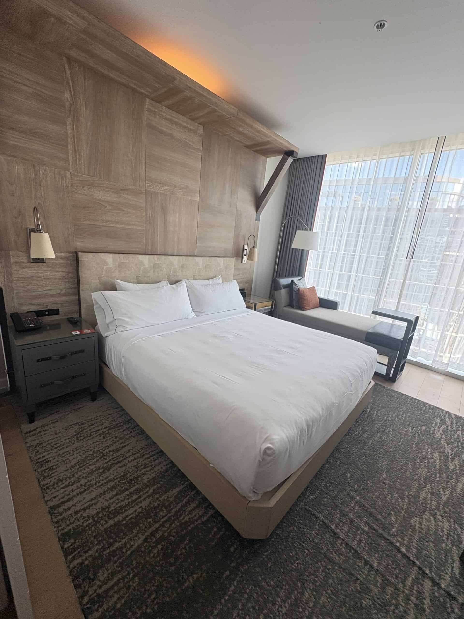 King bed with wood-plank accent wall and warm lighting at Canopy by Hilton Washington DC The Wharf