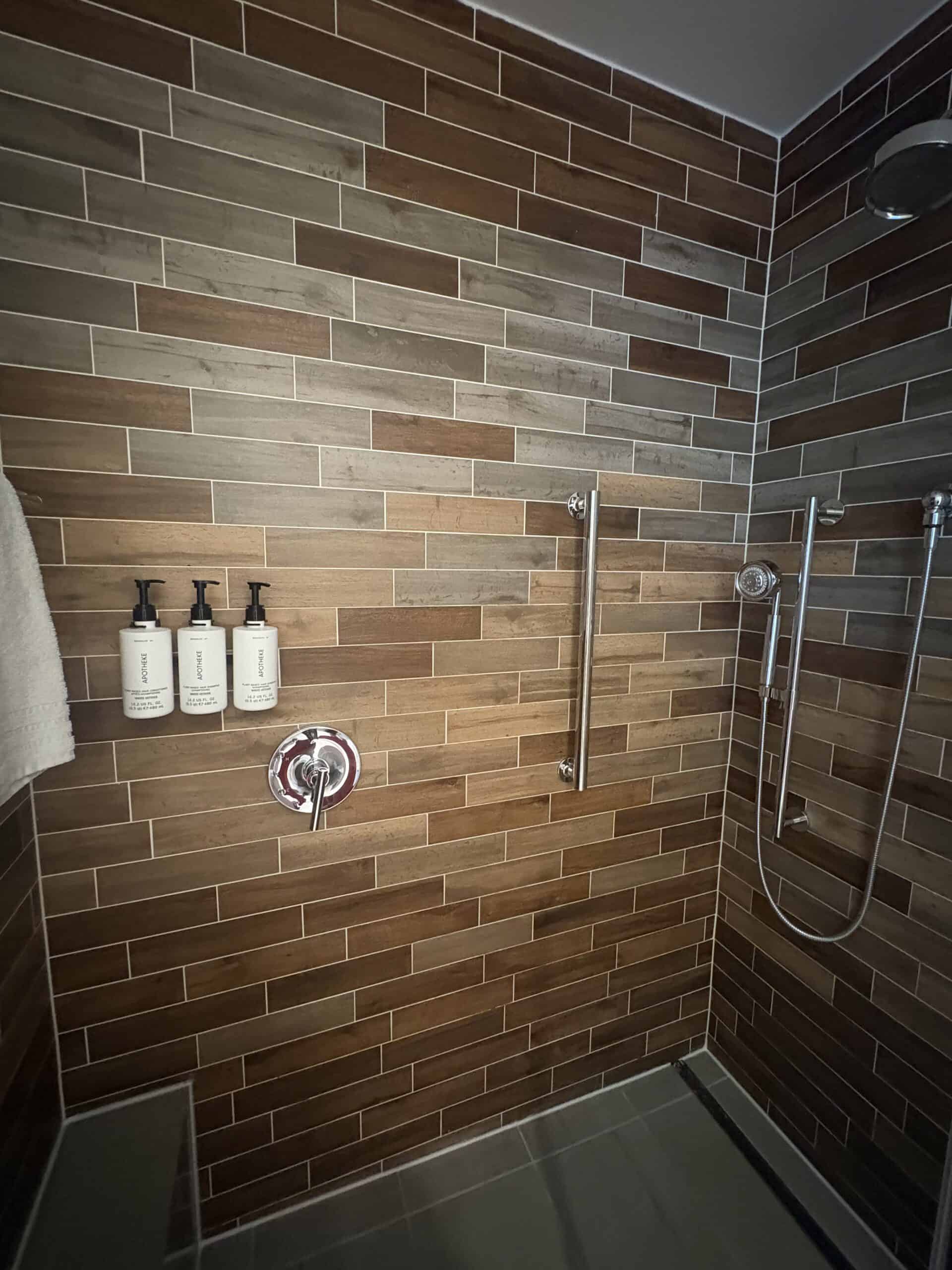 Walk-in shower with wood-look tile and rainfall shower head at Canopy by Hilton Washington DC The Wharf