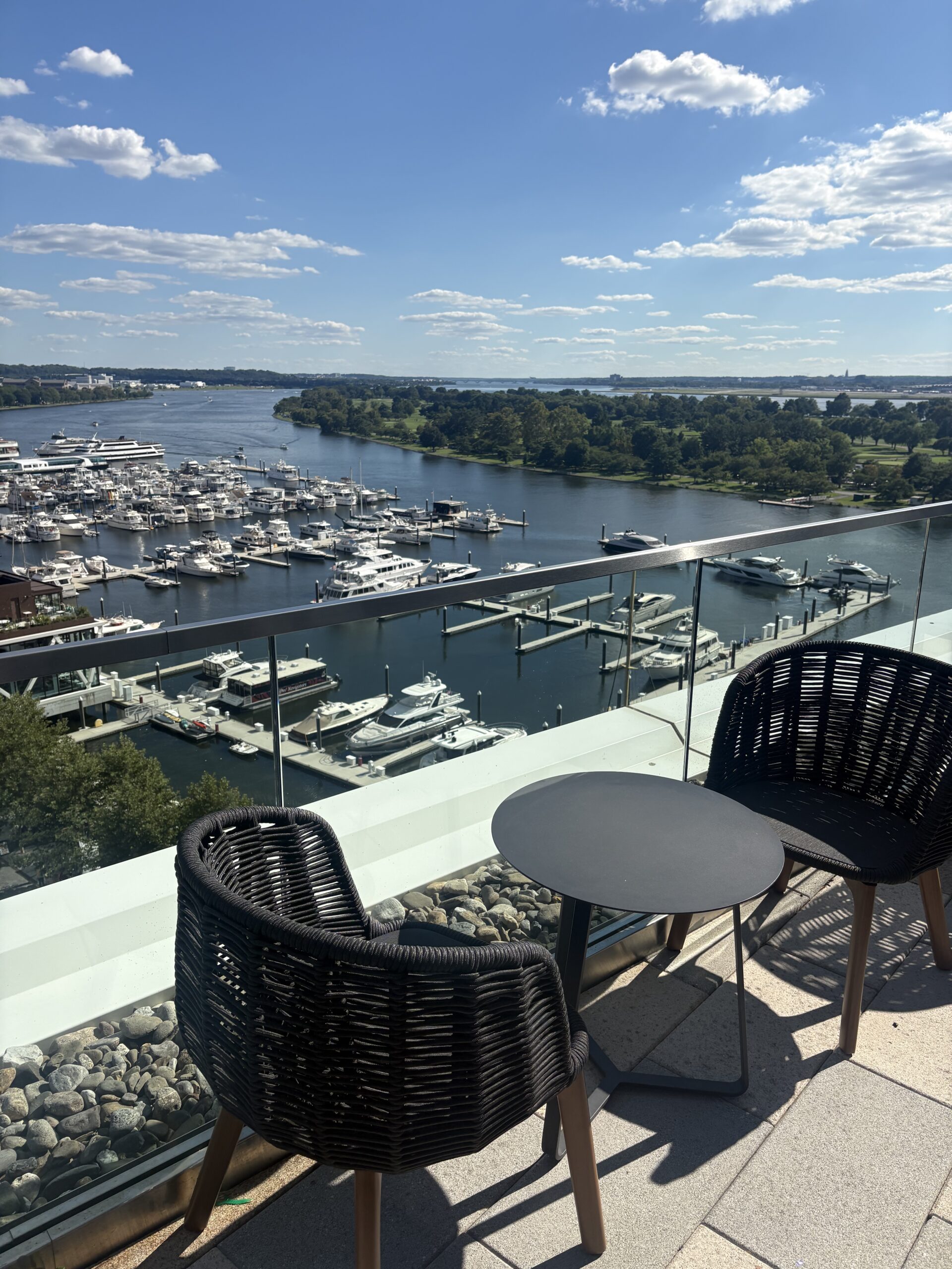 Bistro table and chairs overlooking the marina and Potomac River at Whiskey Charlie rooftop bar, Canopy by Hilton Washington DC The Wharf