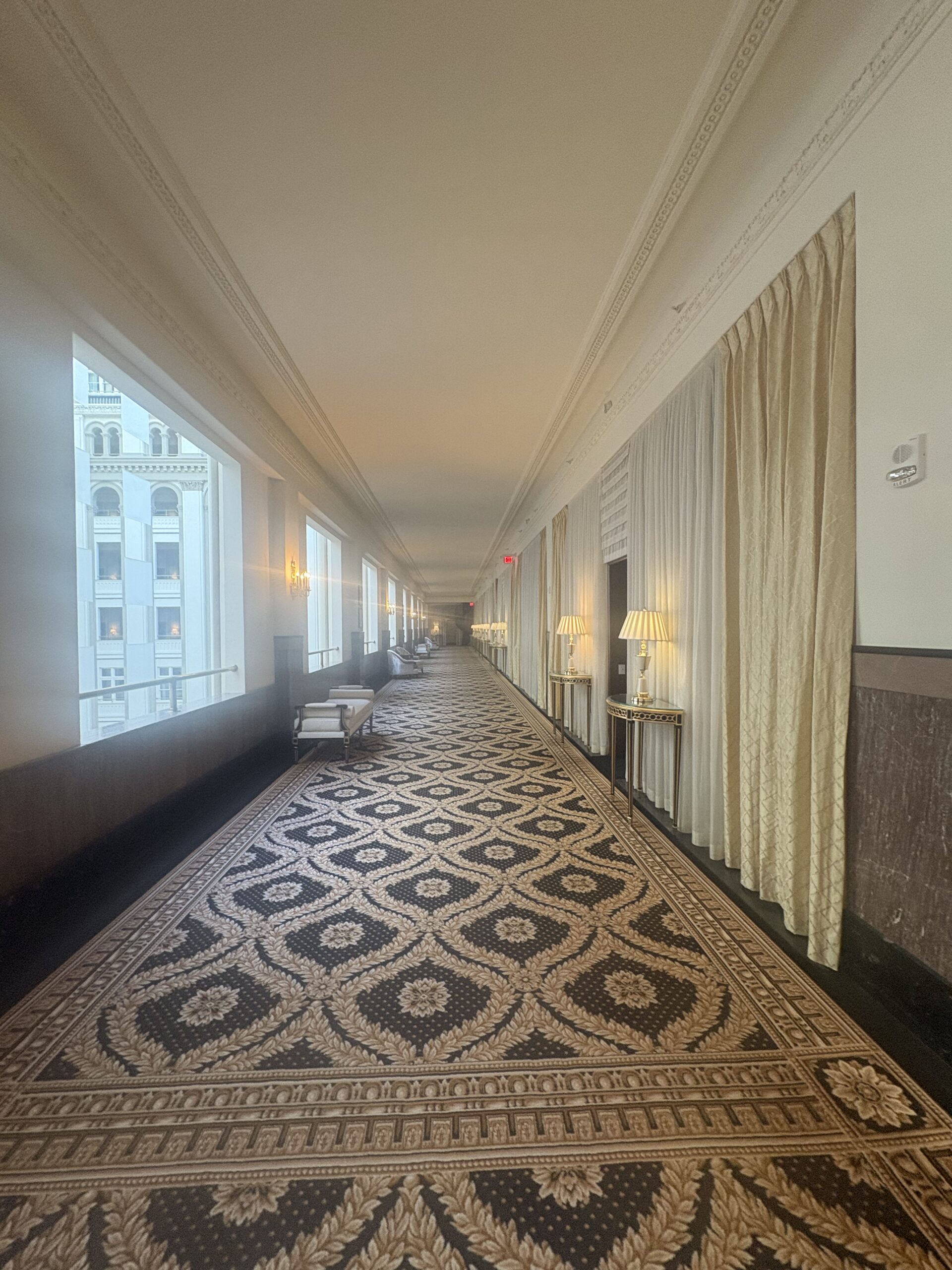 Guest room corridor with patterned curtains and gold sconces at Waldorf Astoria Washington DC