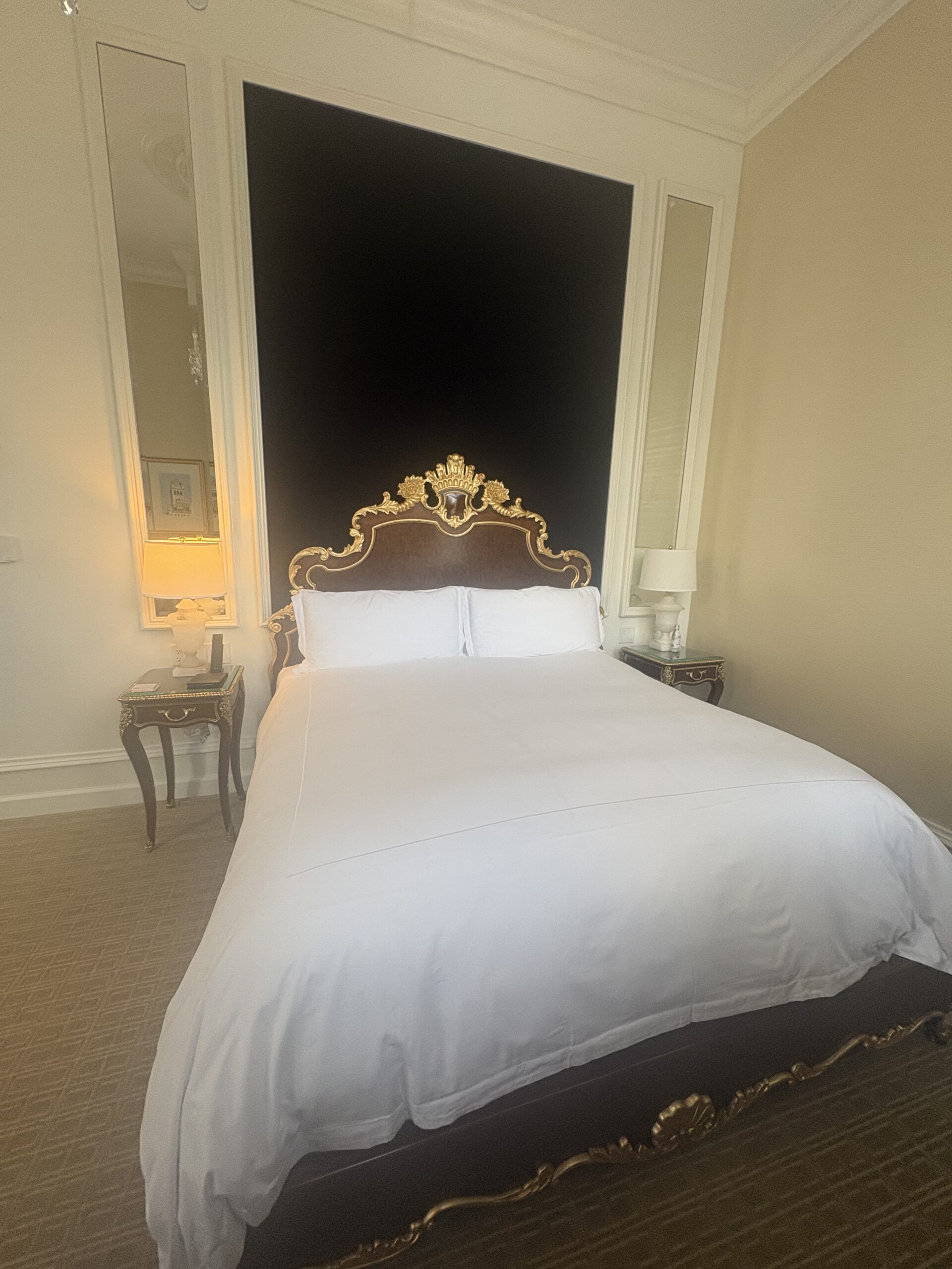 Bed with gilded Rococo-style headboard and mirrored panels at Waldorf Astoria Washington DC